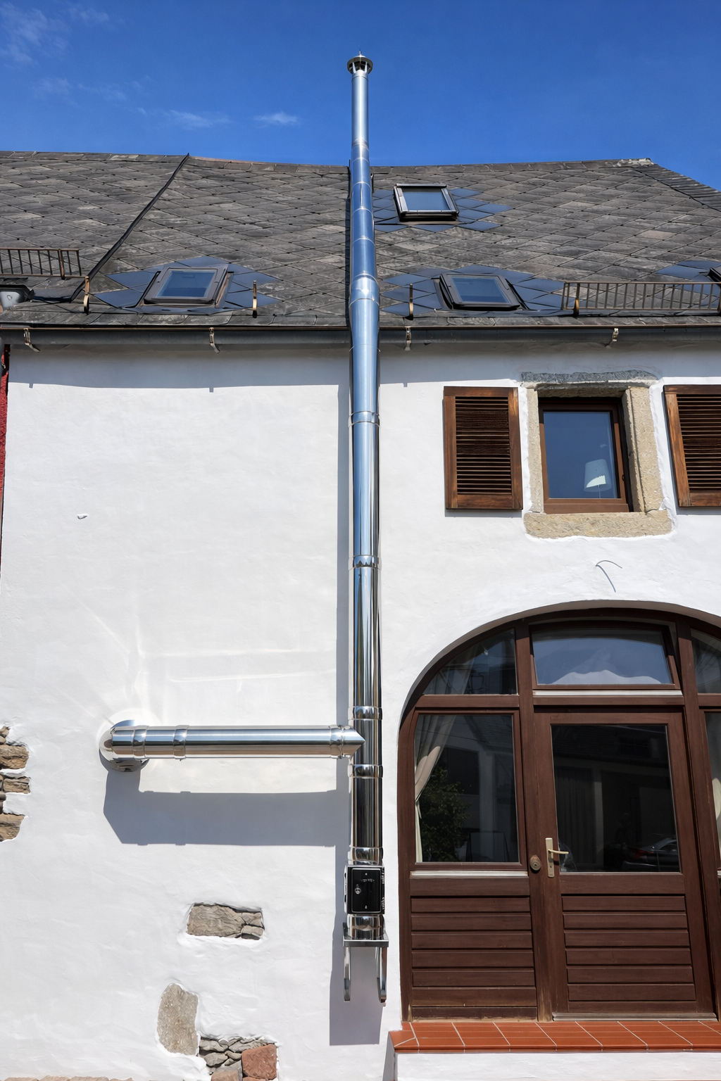 Doppelwandiger Edelstahl-Außenkamin an der Giebelseite eines Wohnhauses