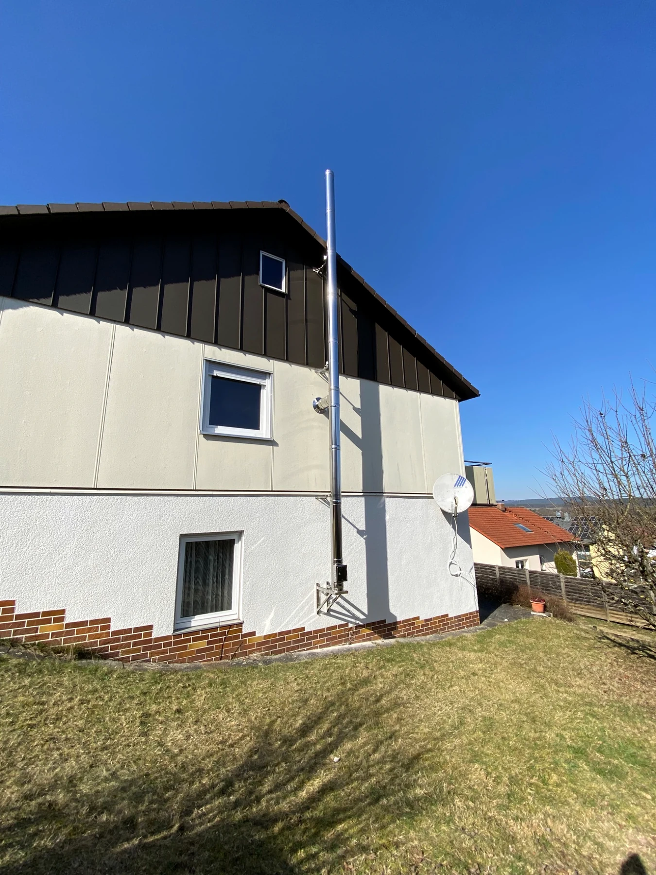 Seitliche Gesamtansicht des Edelstahl-Außenwandkamins am Einfamilienhaus
