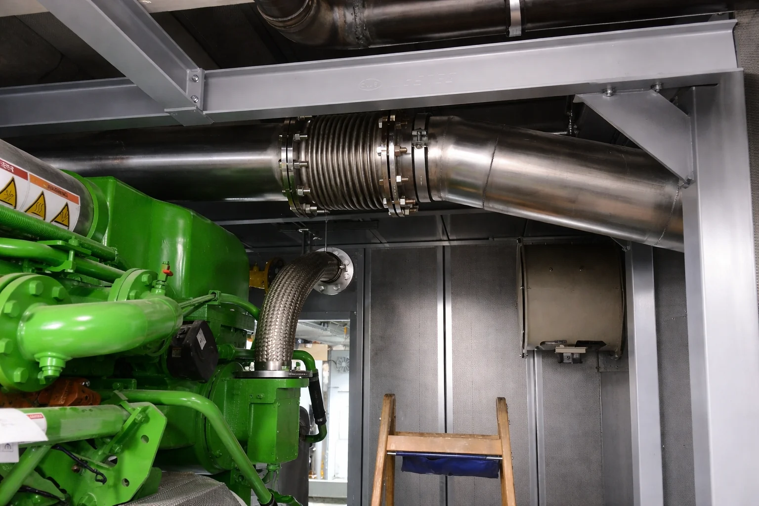 Edelstahlkompensator an der Abgasleitung direkt über einem Jenbacher-Gasmotor