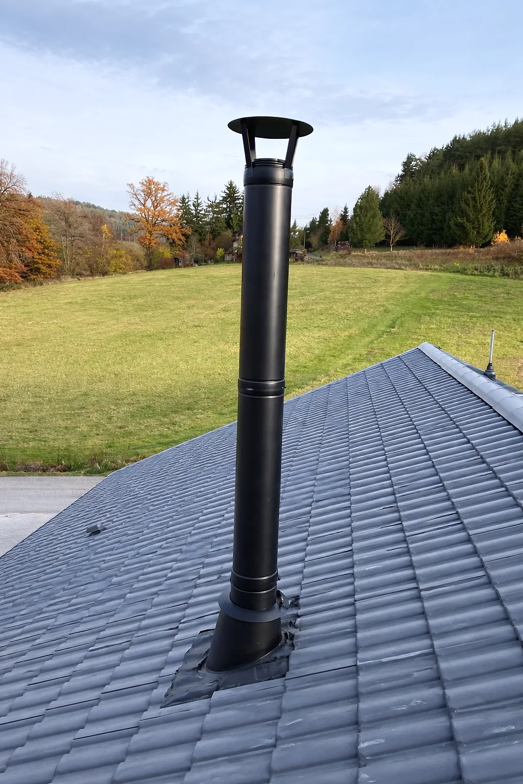 Schwarzer doppelwandiger Edelstahlschornstein auf dem Dach eines Neubaus